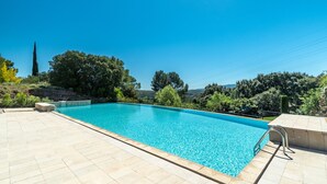 Ein rechteckiger Swimmingpool mit klarem, blauem Wasser, umgeben von einer gefliesten Terrasse.
