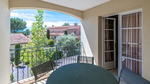 En balkon med udsigt til omkringliggende bygninger og træer.