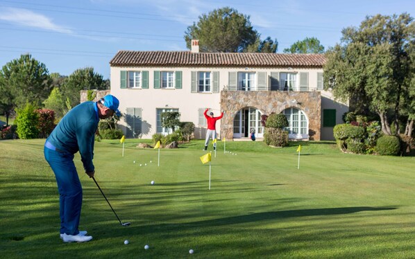Un campo de golf con una casa al fondo.