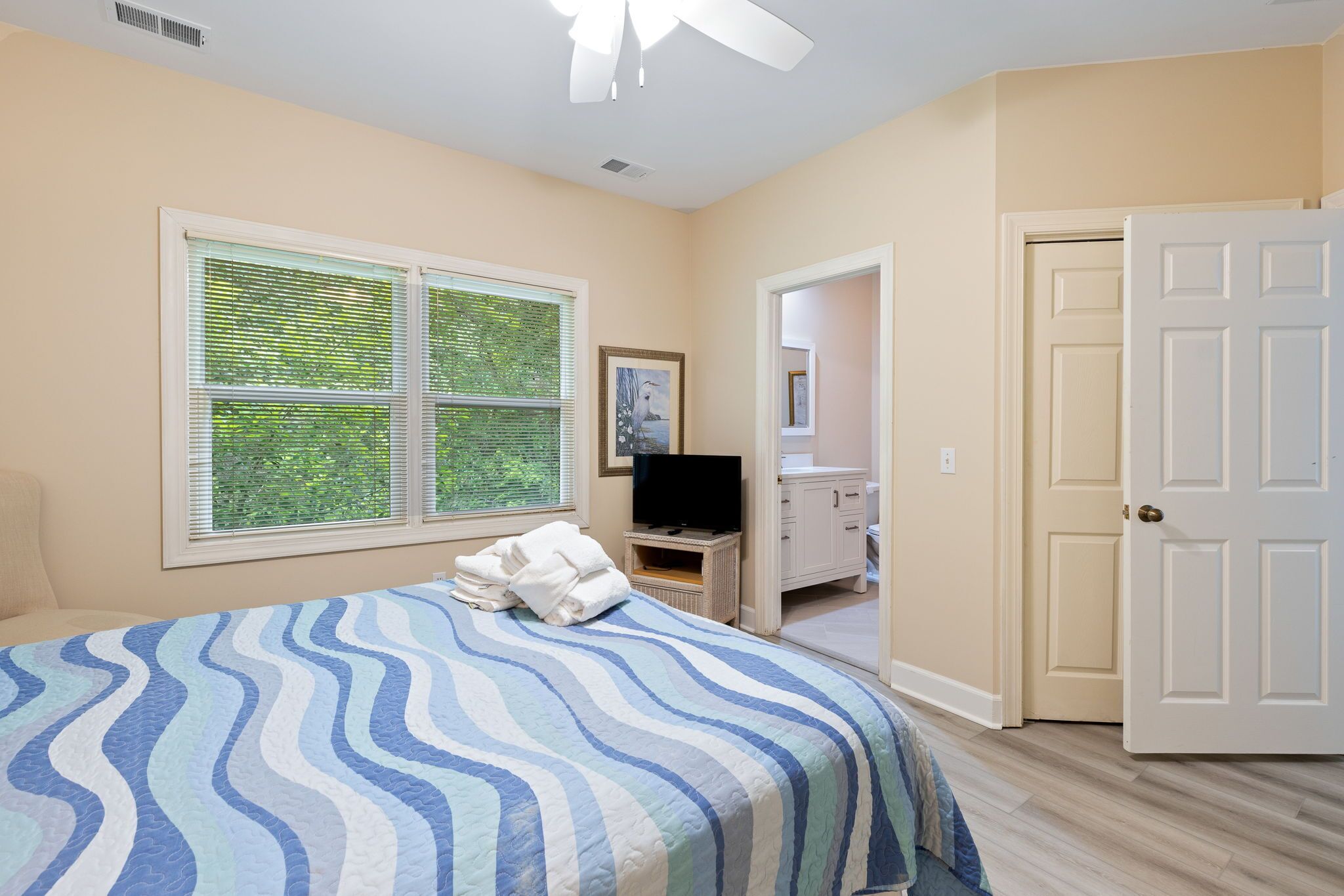Un dormitorio con cama, televisor, cómoda y puerta.