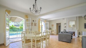 A spacious living room with a dining area, a fireplace, and a view of a pool. - 4 BEDROOM VILLA - PRIVATE POOL AND GARDEN (N°348) (La Motte)