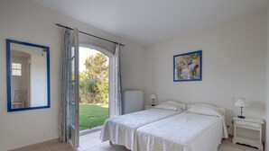 A bedroom with two beds, a window with curtains, a painting on the wall, and a nightstand with a lamp. - 5 BEDROOM VILLA WITH PRIVATE POOL AND GARDEN (N°359) (La Motte)
