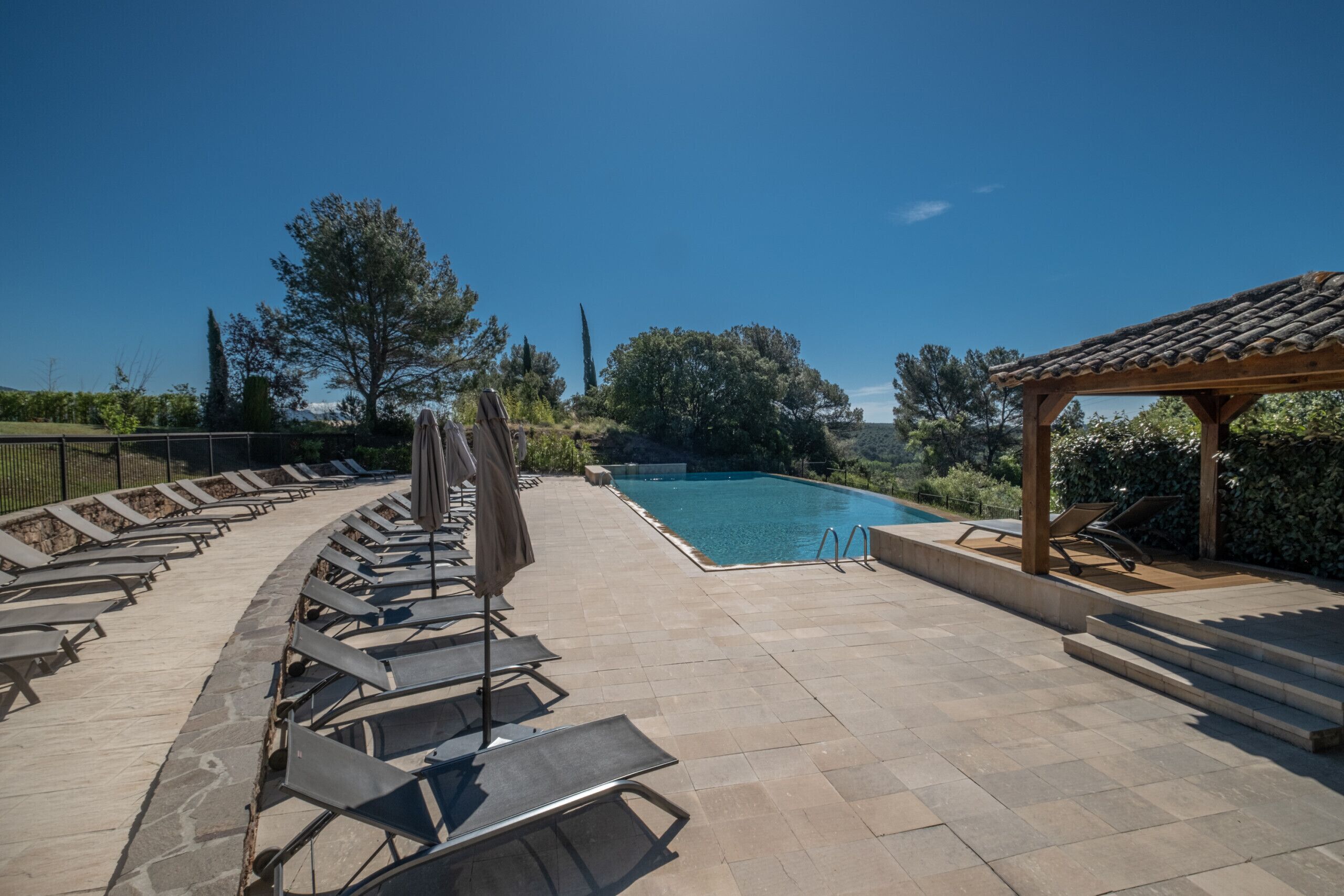 A poolside area with lounge chairs and a pergola.