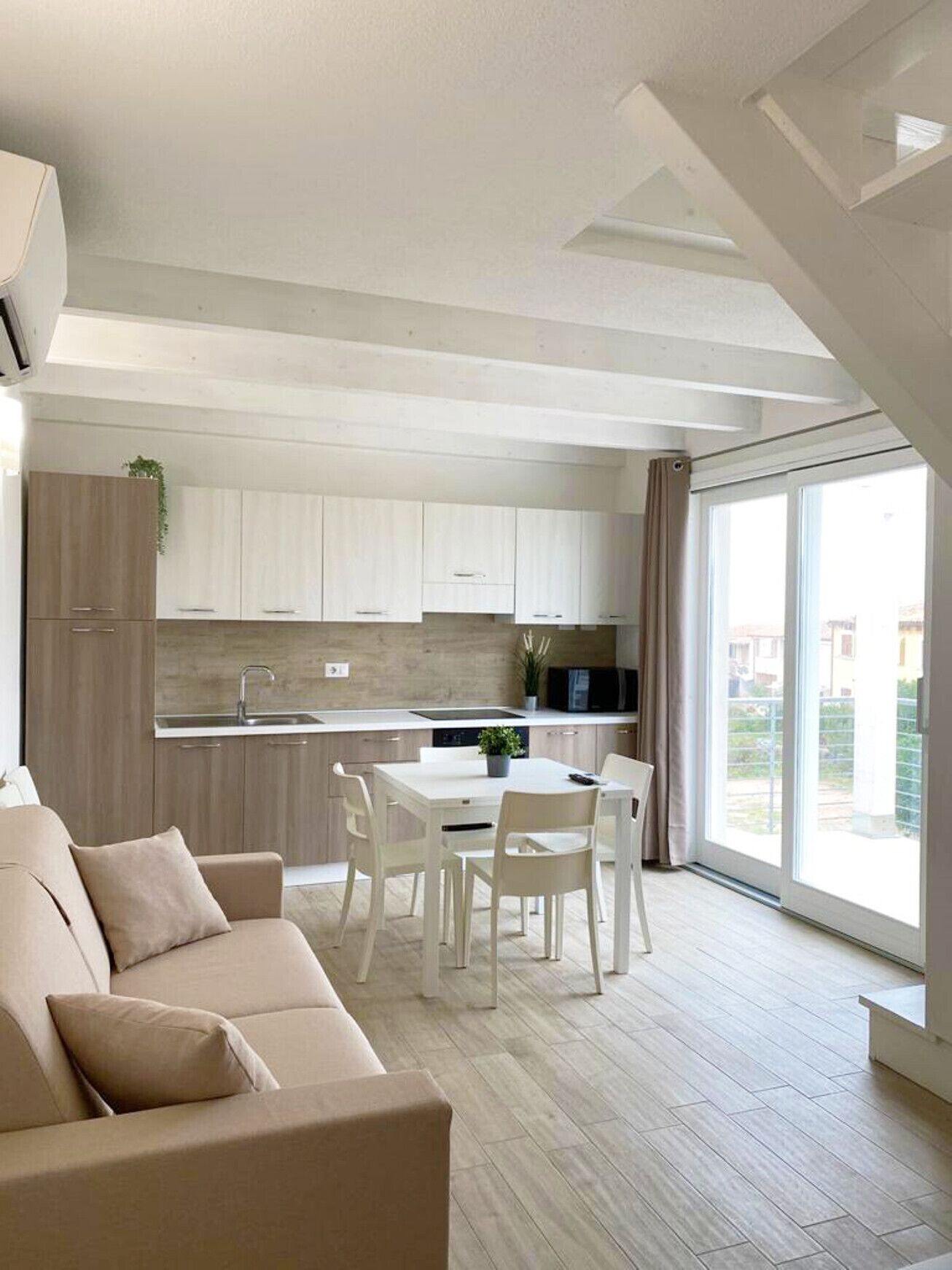 A modern apartment with a dining area, kitchenette, and a large window providing a view of the outside.