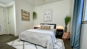 A bedroom with a bed, nightstands, a rug, and wall art. - Heart of Downtown - Bike Friendly - Ground Level (Bentonville)