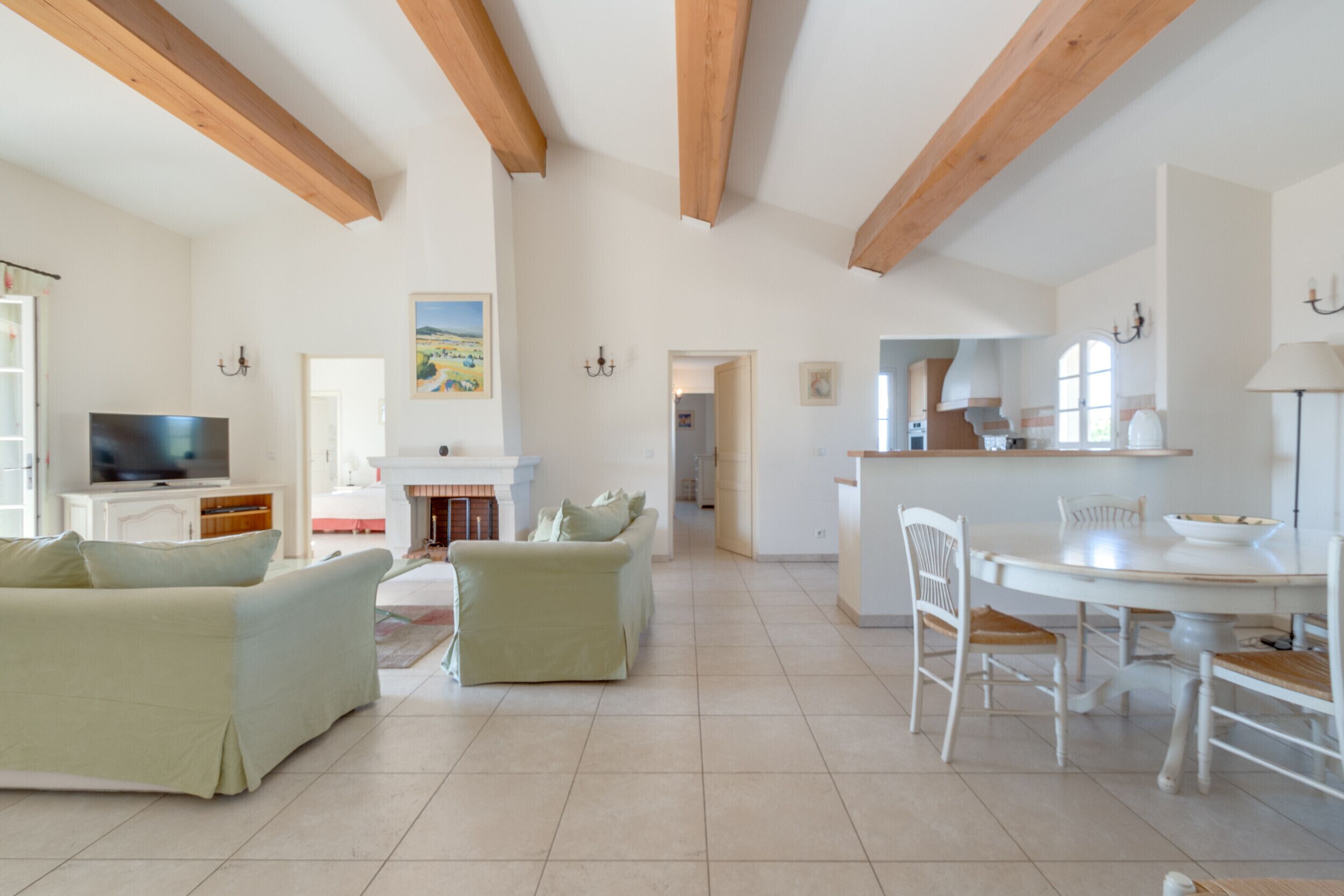 Un grand salon doté d’une cheminée, d’une table à manger avec des chaises et d’un téléviseur placé dans un coin.