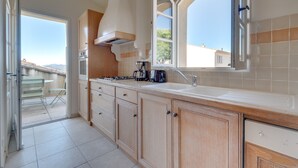 Una cocina moderna con armarios de madera, horno empotrado y un amplio ventanal con vistas al exterior.