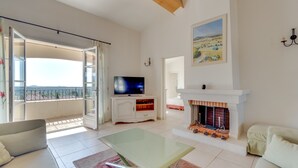 Un amplio salón con balcón, chimenea y televisor.