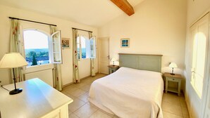 Un dormitorio con cama, dos mesitas de noche, un escritorio y una ventana con cortinas.