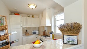 A kitchen with white cabinets, a microwave, and a bowl of fruit on the counter. - 2-BEDROOM APARTMENT WITH TERRACE (N°555) (La Motte)