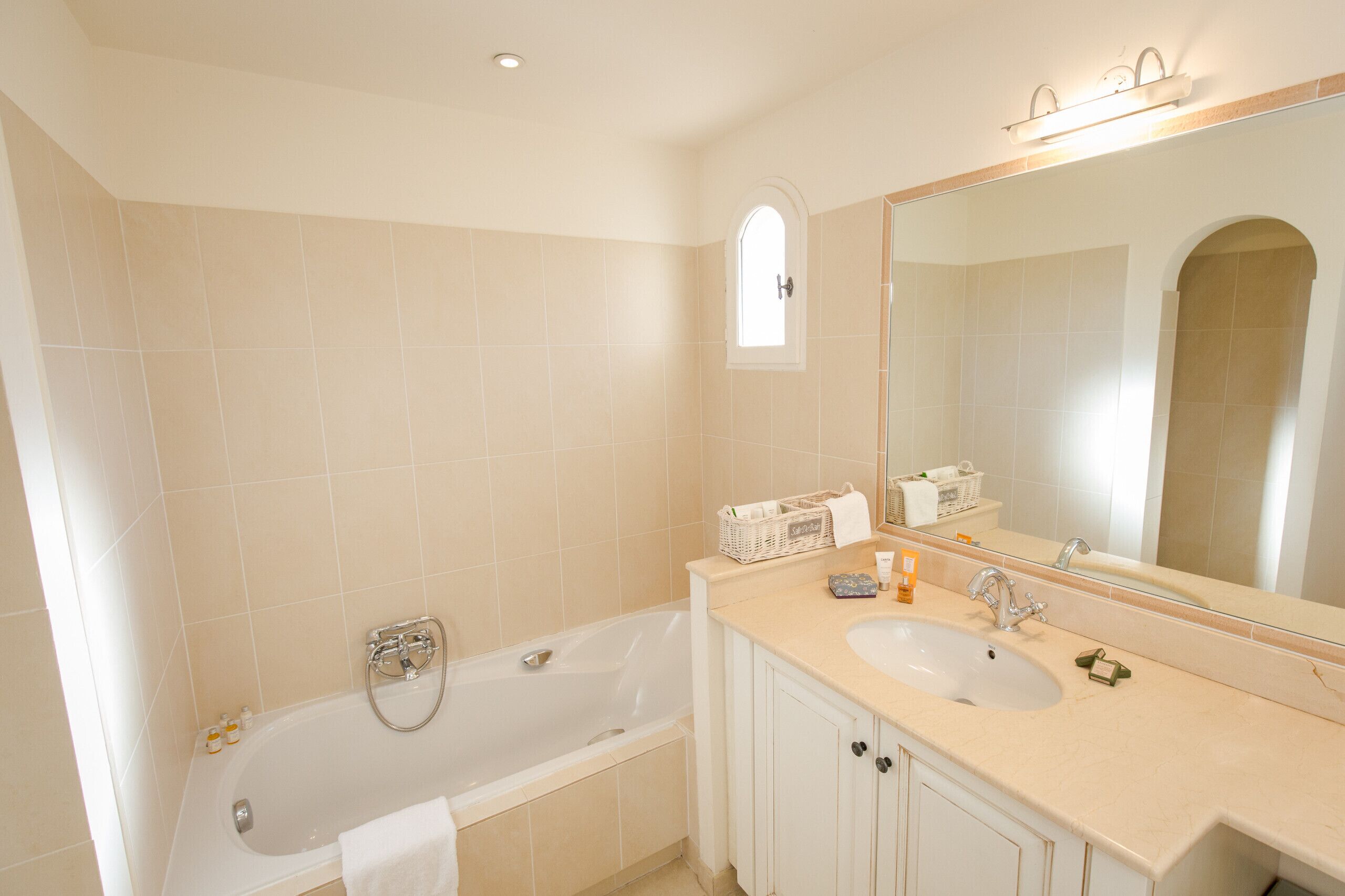 A bathroom with a bathtub, two sinks, a large mirror, and a window.