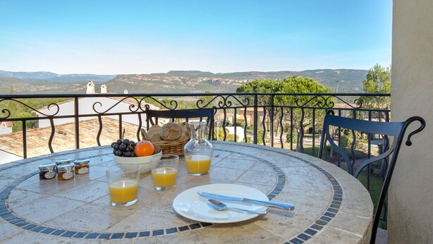 A round table with breakfast items, a view of hills, and a balcony railing. - 2-BEDROOM APARTMENT WITH TERRACE (N°555) (La Motte)