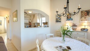 A dining area with a round table, chairs, a chandelier, and a vase with flowers. - 2-BEDROOM APARTMENT WITH TERRACE (N°555) (La Motte)