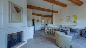 A spacious living room with a fireplace, a dining area, and a kitchen in the background. - 3 BEDROOM TOWNHOUSE WITH GARDEN (N°565) (La Motte)