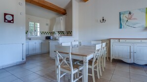 A spacious kitchen with white cabinetry, a wooden dining table, and chairs. - 3 BEDROOM TOWNHOUSE WITH GARDEN (N°565) (La Motte)