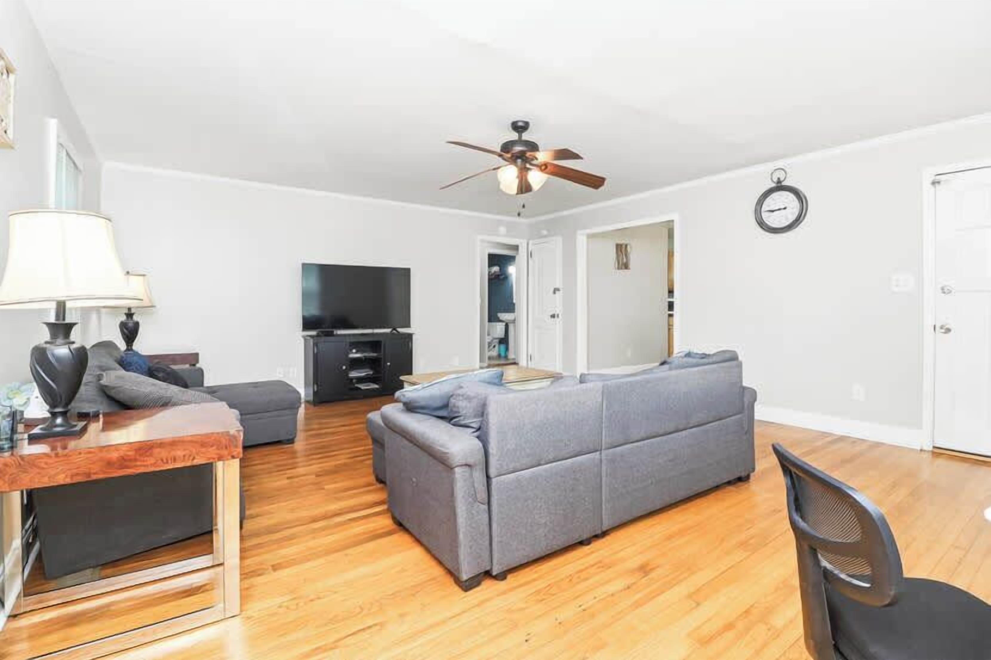 A modern living room with a sofa, a television, and a ceiling fan.