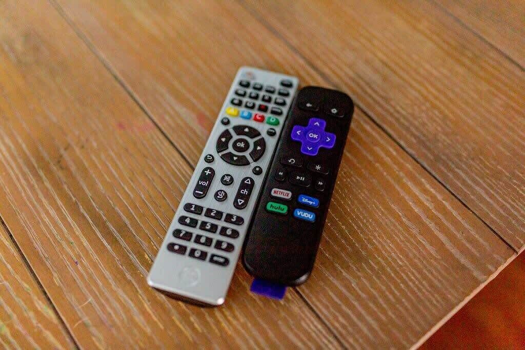 Two remote controls on a wooden surface.