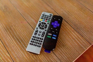 Two remote controls on a wooden surface.