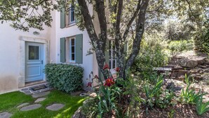 A house with a stone pathway leading to the entrance, surrounded by greenery and a small garden. - 3 BEDROOM TOWNHOUSE WITH GARDEN (N°329) (La Motte)