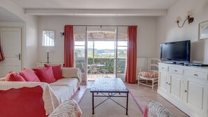 A room with a bed, a sofa, a television, and a view through a glass door. - 3 BEDROOM TOWNHOUSE WITH GARDEN (N°329) (La Motte)