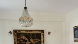 Huoneessa on valkoinen sohva, puulattia, kattokruunu ja seinällä oleva taulu, joka on kehystetty.