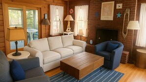 A cozy living room with a fireplace, a sofa, a blue armchair, and a coffee table.