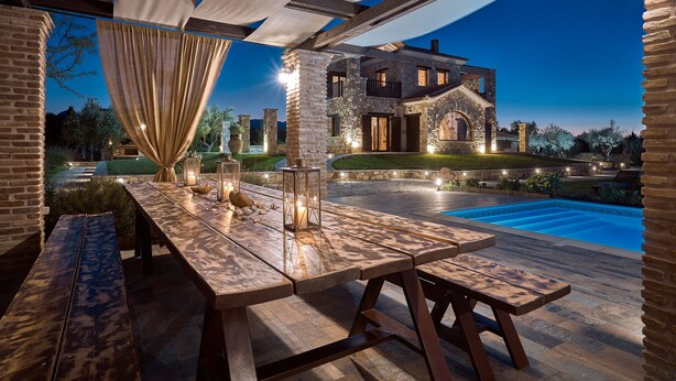 An outdoor patio with a pool, stone house, and dining area with tables and benches. - Palazzo Villa, World 5th Awarded Villa (Zakynthos)