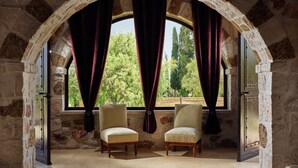 A room with an arched stone ceiling, two upholstered chairs, and a large window with curtains. - Palazzo Villa, World 5th Awarded Villa (Zakynthos)