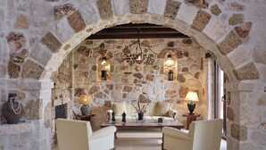 A cozy room with stone walls, a wooden ceiling, two armchairs, a sofa, a coffee table, and a chandelier. - Palazzo Villa, World 5th Awarded Villa (Zakynthos)