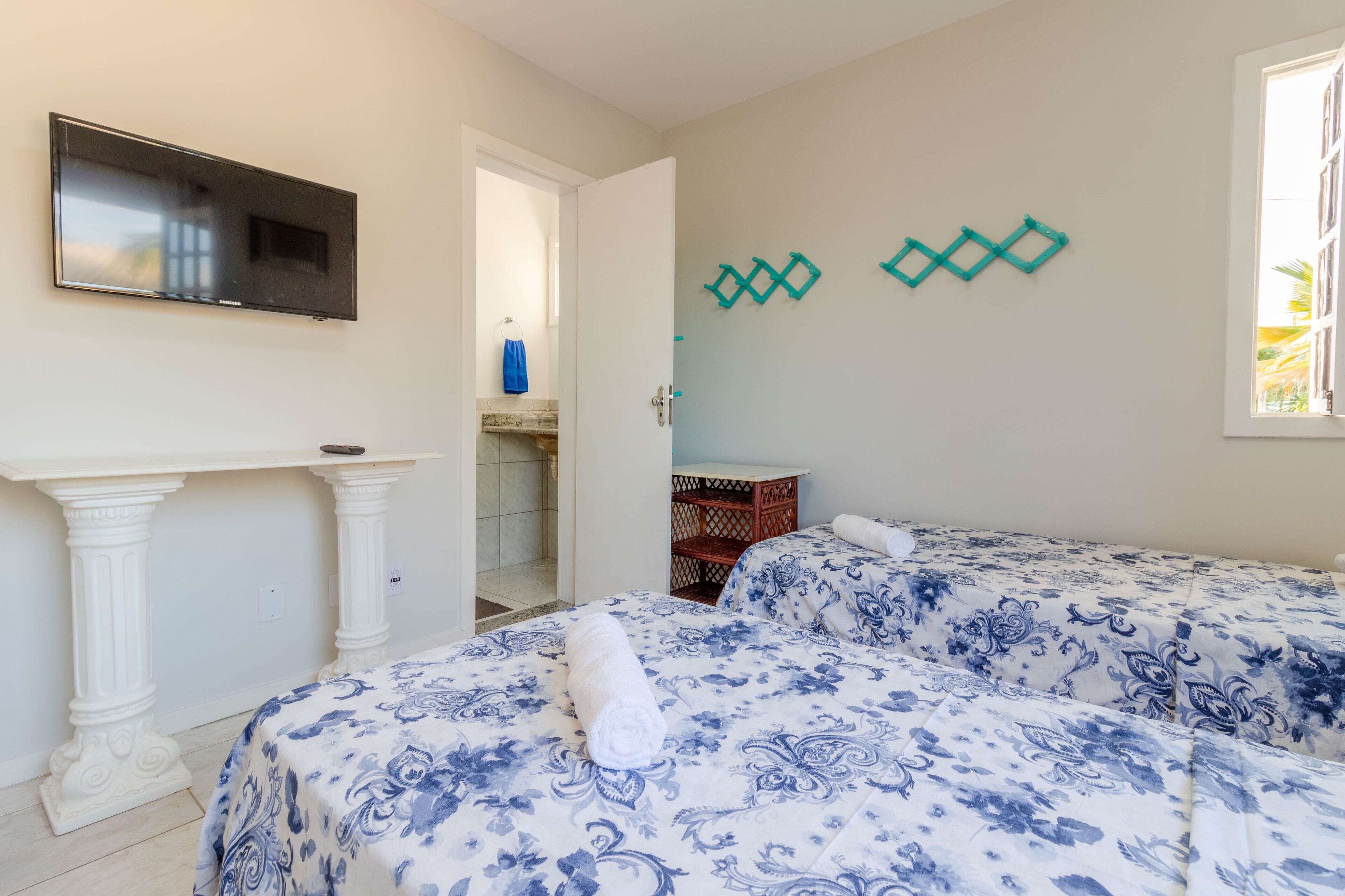A hotel room with two beds, a TV, a small table, and a window.