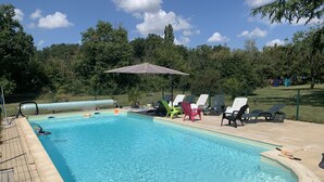 Ein Schwimmbecken mit Liegestühlen und einer beschatteten Liegefläche.