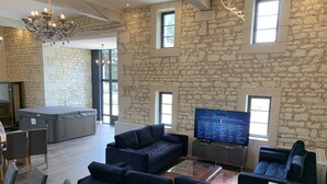 Ein geräumiger Wohnbereich mit Steinwänden, einer großen Couch, einem Fernseher und einer Whirlwanne.