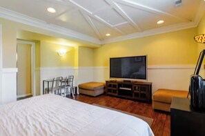 Une chambre d’hôtel avec un grand lit, un téléviseur à écran plat, un coin salon avec des fauteuils et une petite table.