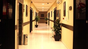 A hotel corridor with a long, polished floor, recessed lighting, and potted plants. - Rest Night Serviced Apartments - AL Nafal رست نايت للشقق المخدومة - النفل (Riyadh)