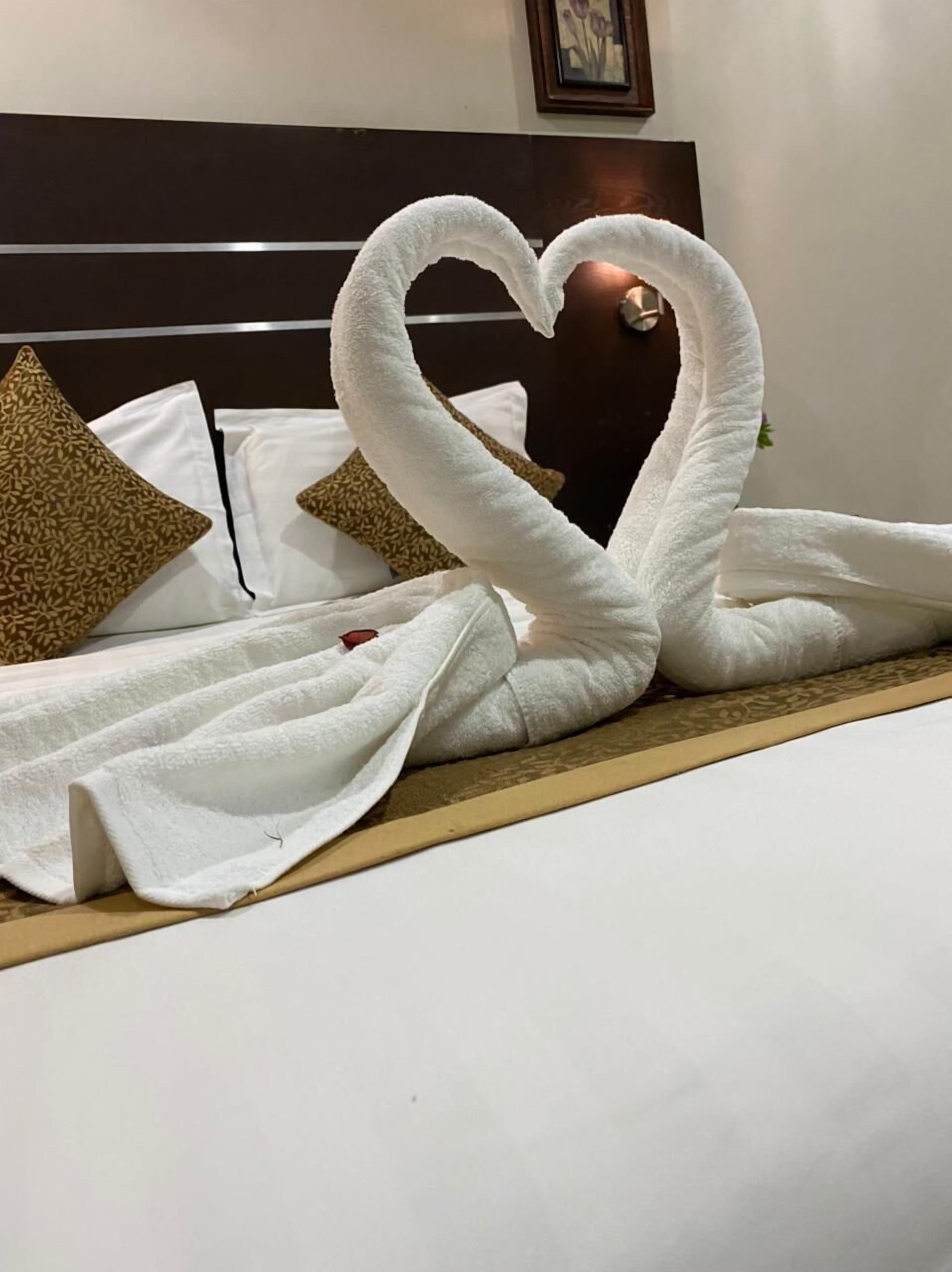 Un lit décoré avec des serviettes disposées en forme de cœur.