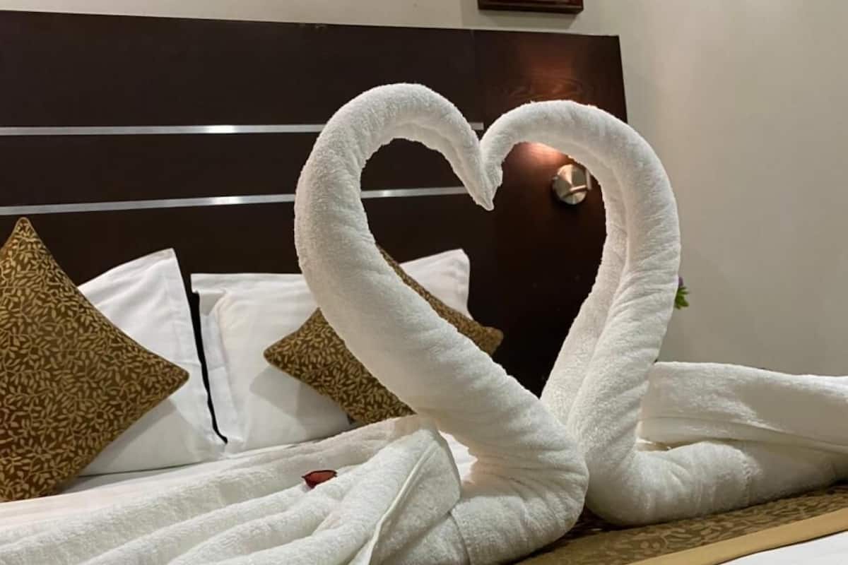 Un lit décoré avec des serviettes disposées en forme de cœur.