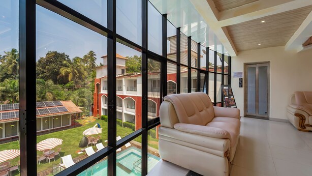Ein modernes Hotelzimmer mit großen Fenstern, einem Pool und Blick auf ein Gebäude mit Palmen.