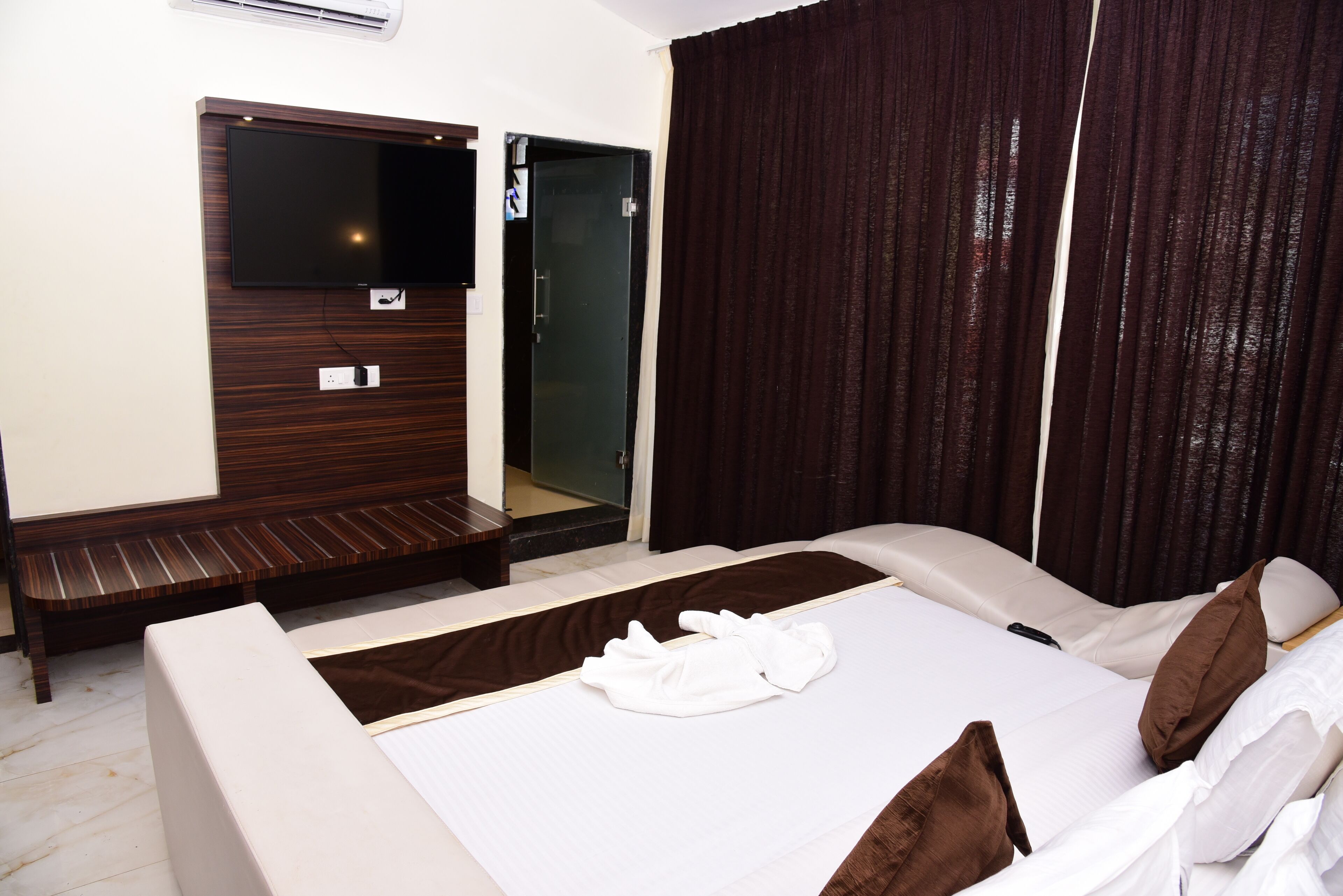 Une chambre d’hôtel comprenant un lit, un coin salon, une télévision et une porte.