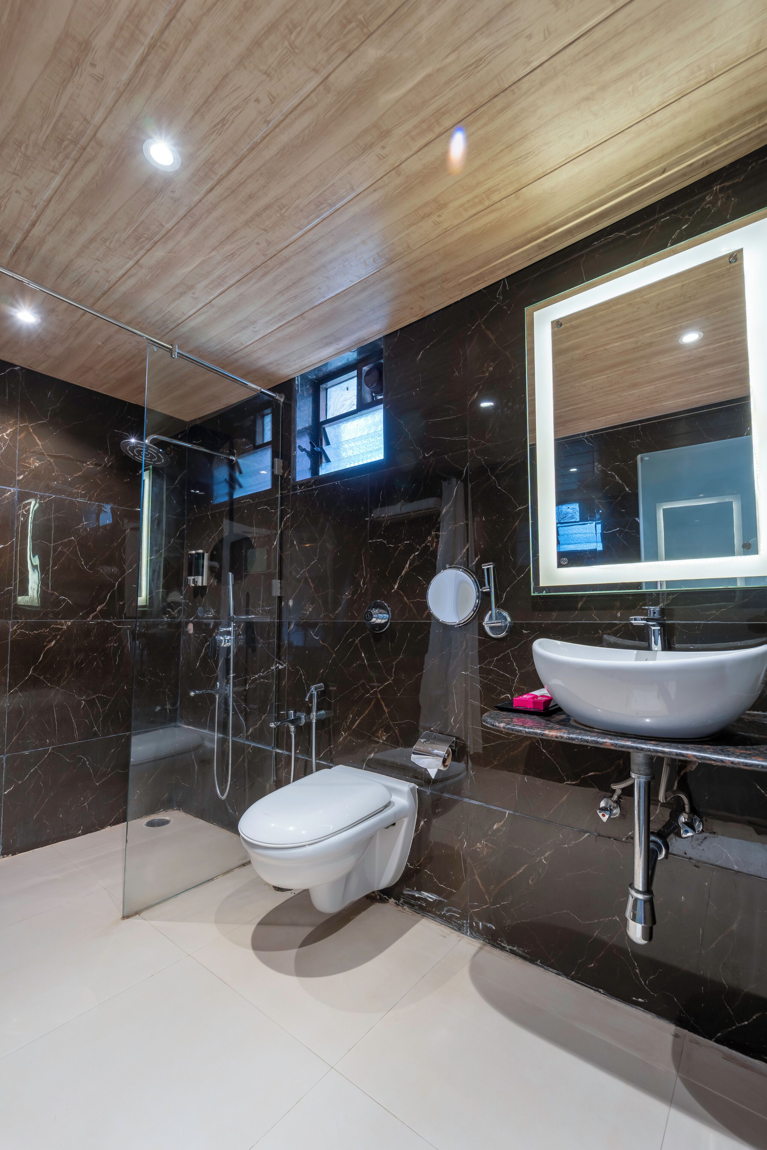 Un baño moderno con ducha de vidrio, inodoro blanco y tocador con un espejo grande.