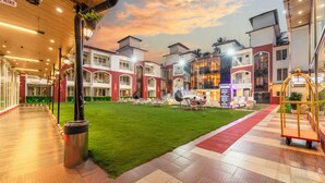 Ein Hotelinnenhof mit grünem Rasen, Sitzgelegenheiten im Freien und einer Rezeption.