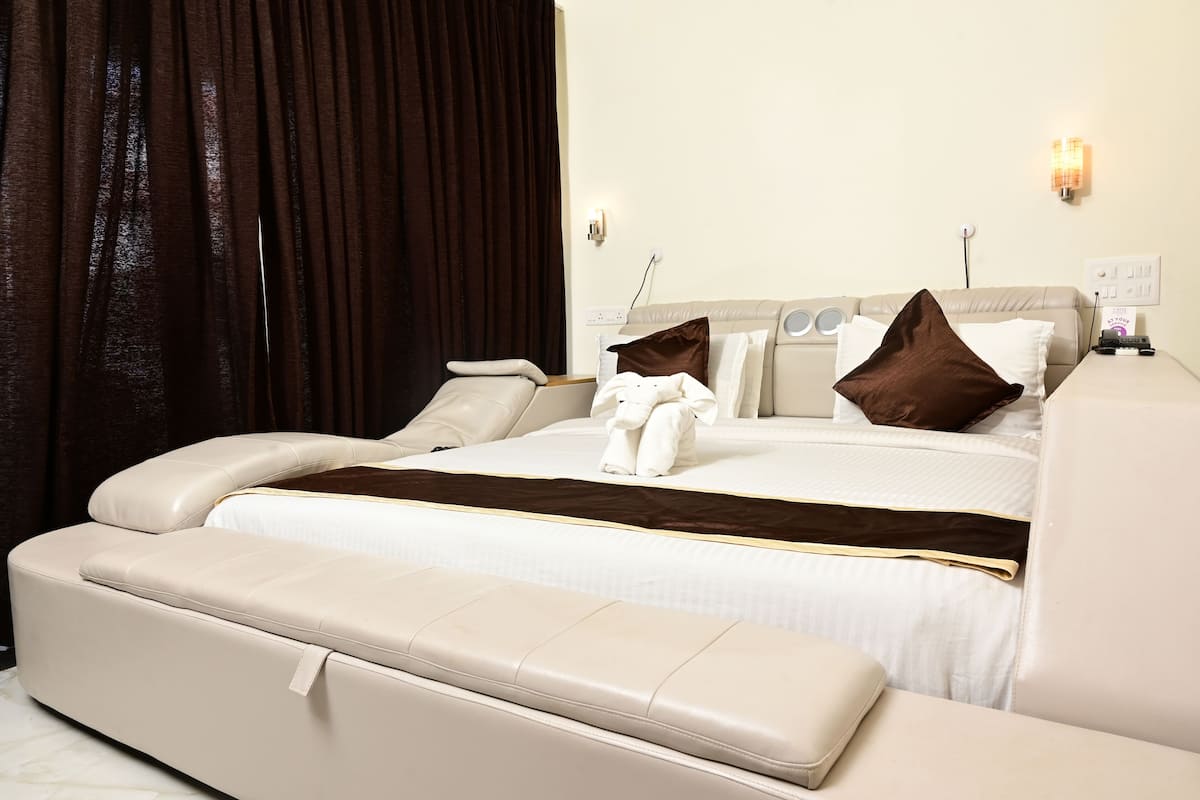 A modern hotel room with a large bed, a sofa, and a bench.
