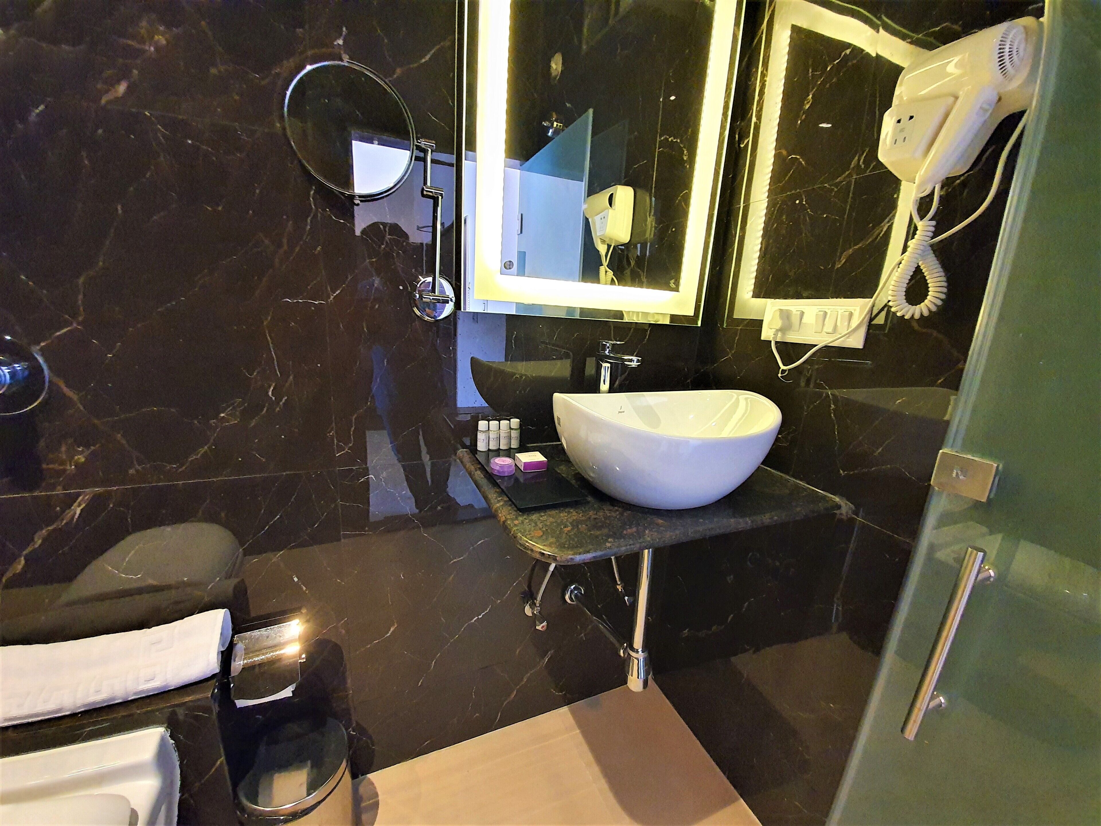 A bathroom with a white sink, a mirror, a hairdryer, and a towel rack.