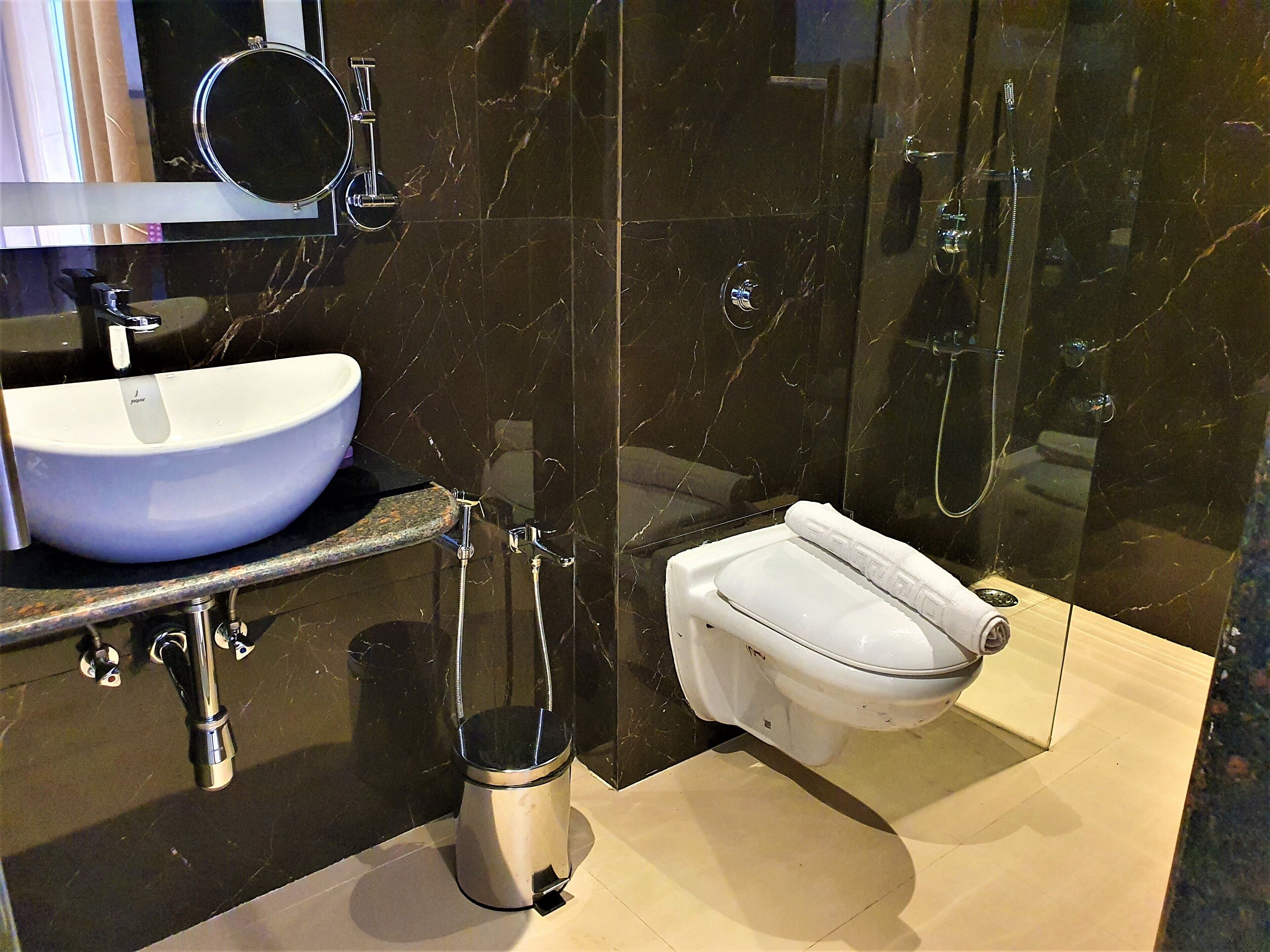 Een moderne badkamer met een wit wastafel, toilet en douche.