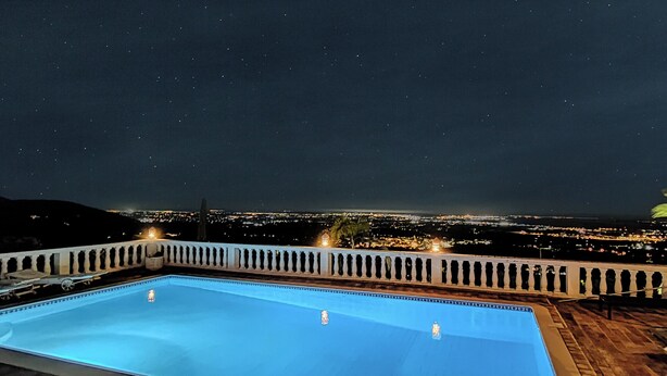 A swimming pool with a night view of a cityscape in the background.