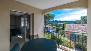 A balcony with a table and chairs, a view of a residential area, and a door leading to an interior room. - 2 BEDROOM APARTMENT WITH TERRACE (N°513) (La Motte)