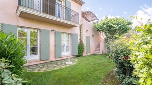 A two-story house with a balcony, a stone pathway, and a well-maintained garden. - 2-BEDROOM TOWNHOUSE WITH GARDEN (N°330) (La Motte)