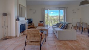 A living room with a fireplace, sofa, and TV. - 2-BEDROOM TOWNHOUSE WITH GARDEN (N°330) (La Motte)