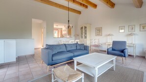 A spacious living room with a blue sofa, white coffee table, and a woven chair. - 2 BEDROOM TOWNHOUSE WITH GARDEN (N°336) (La Motte)
