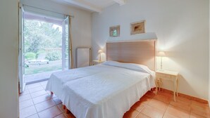 A bedroom with a bed, a nightstand, a lamp, and a window with a view of greenery outside. - 2 BEDROOM TOWNHOUSE WITH GARDEN (N°336) (La Motte)
