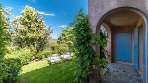 A courtyard with a stone pathway, a blue door, and a grassy area with outdoor furniture. - 2 BEDROOM TOWNHOUSE WITH GARDEN (N°336) (La Motte)